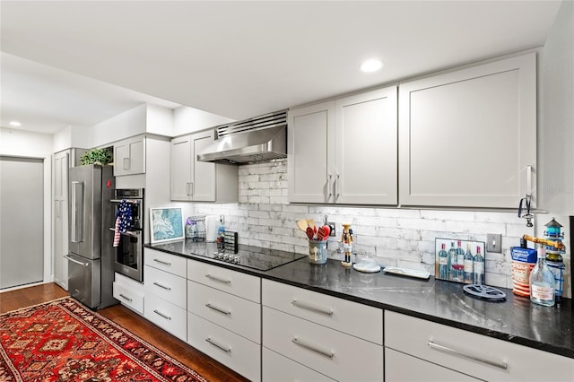 kitchen featuring decorative backsplash, stainless steel appliances, dark hardwood / wood-style flooring, and wall chimney range hood