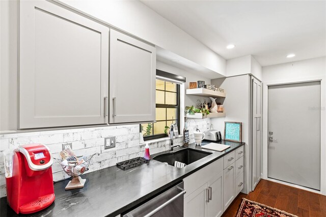 kitchen with stainless steel dishwasher, sink, dark hardwood / wood-style flooring, and tasteful backsplash