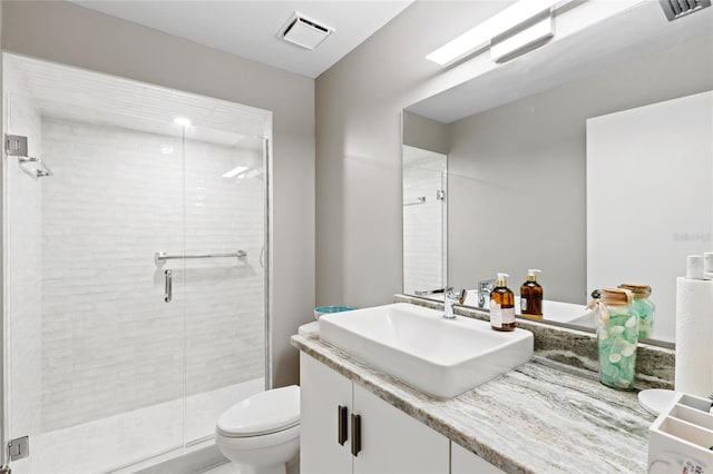 bathroom featuring toilet, vanity, and a shower with shower door