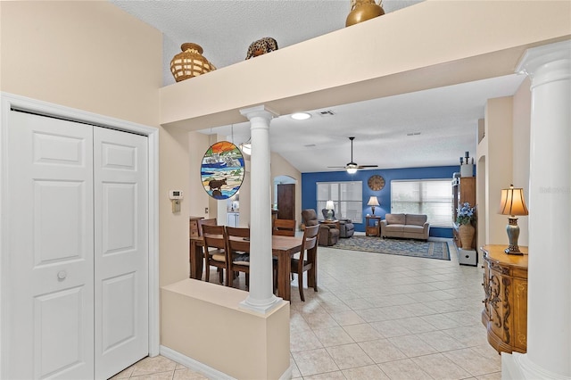 dining area featuring decorative columns, light tile patterned floors, a textured ceiling, and ceiling fan