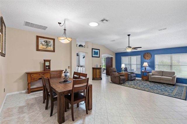 tiled dining room featuring ceiling fan, vaulted ceiling, and a textured ceiling