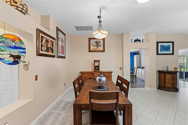 tiled dining room featuring a textured ceiling