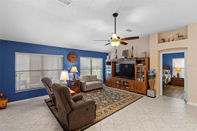 tiled living room featuring lofted ceiling, ceiling fan, and a textured ceiling