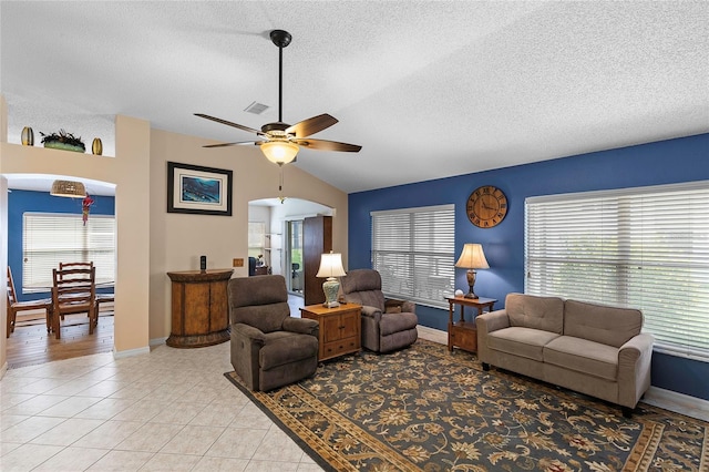 living room with vaulted ceiling, light tile patterned floors, ceiling fan, and a textured ceiling