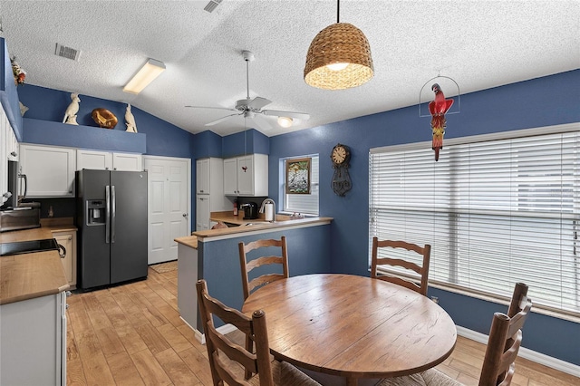 kitchen featuring vaulted ceiling, light wood-type flooring, appliances with stainless steel finishes, a wealth of natural light, and white cabinets