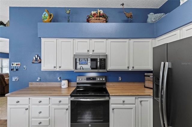 kitchen with wood counters, appliances with stainless steel finishes, and white cabinets