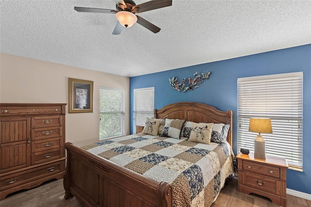 bedroom with hardwood / wood-style flooring, a textured ceiling, and ceiling fan