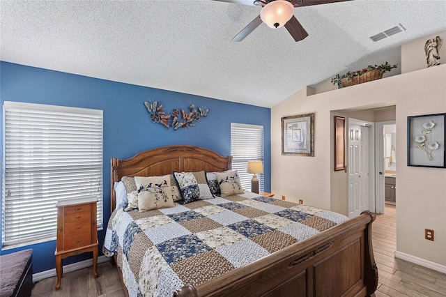 bedroom with ceiling fan, wood-type flooring, a textured ceiling, and lofted ceiling