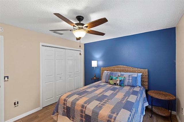 bedroom featuring hardwood / wood-style flooring, a textured ceiling, a closet, and ceiling fan