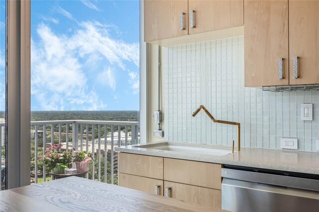 kitchen with stainless steel dishwasher, light brown cabinetry, sink, and decorative backsplash