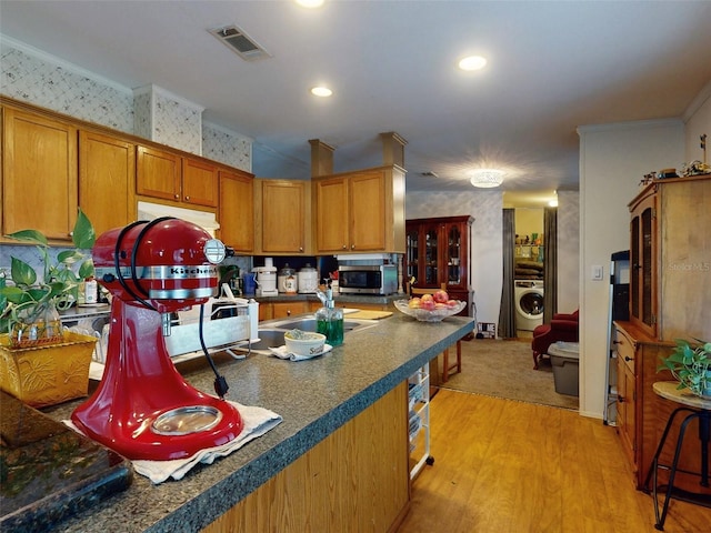 kitchen featuring washer / clothes dryer, light hardwood / wood-style flooring, sink, and ornamental molding