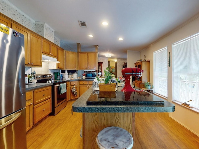 kitchen featuring a center island, appliances with stainless steel finishes, light wood-type flooring, and tasteful backsplash