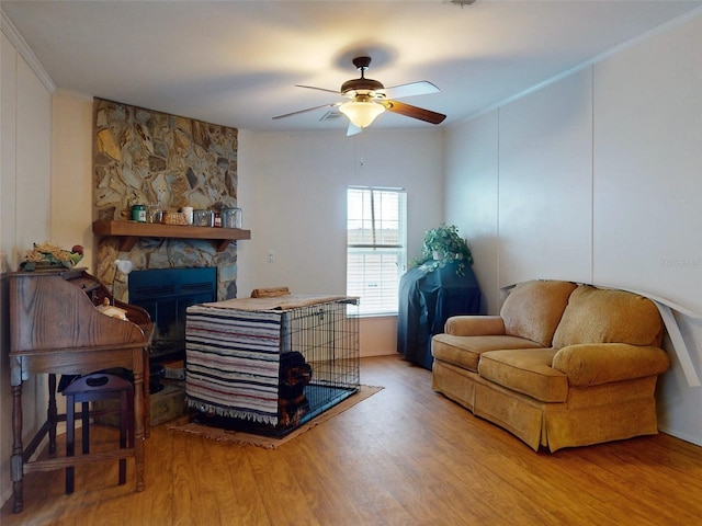 living room with a fireplace, light wood-type flooring, and ceiling fan