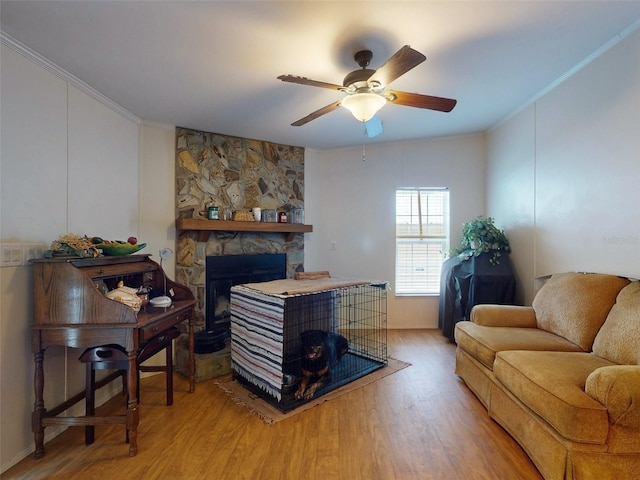 living room featuring a stone fireplace, ceiling fan, and light wood-type flooring