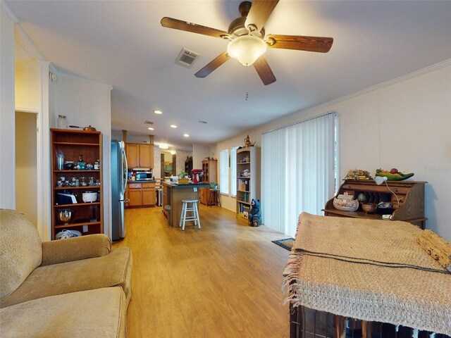 living room with light hardwood / wood-style floors, ceiling fan, and crown molding