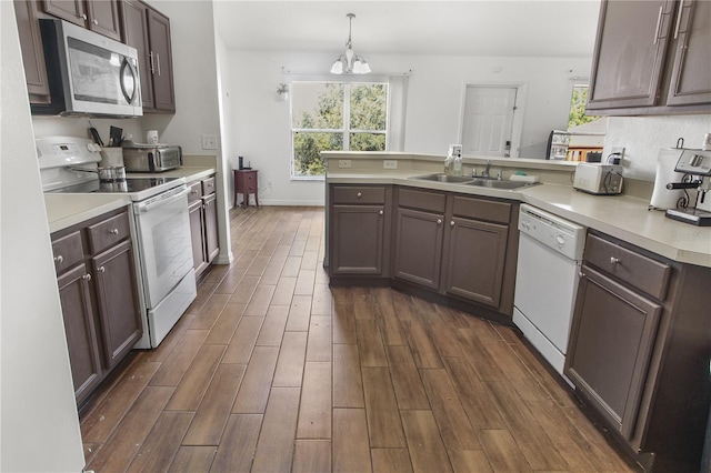 kitchen with sink, hanging light fixtures, white appliances, kitchen peninsula, and an inviting chandelier