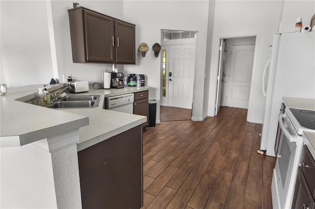 kitchen featuring dark brown cabinets, sink, white appliances, and kitchen peninsula