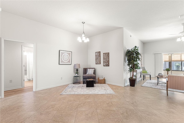 sitting room featuring ceiling fan with notable chandelier, light tile patterned flooring, and a textured ceiling