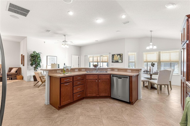 kitchen featuring stainless steel dishwasher, sink, pendant lighting, lofted ceiling, and an island with sink