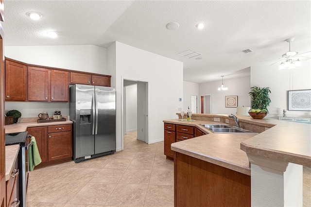 kitchen with a textured ceiling, stainless steel appliances, sink, pendant lighting, and lofted ceiling