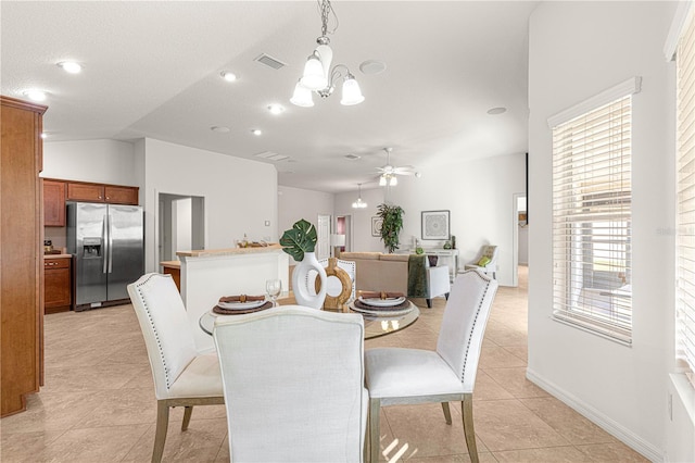 dining room with light tile patterned floors, ceiling fan with notable chandelier, and vaulted ceiling