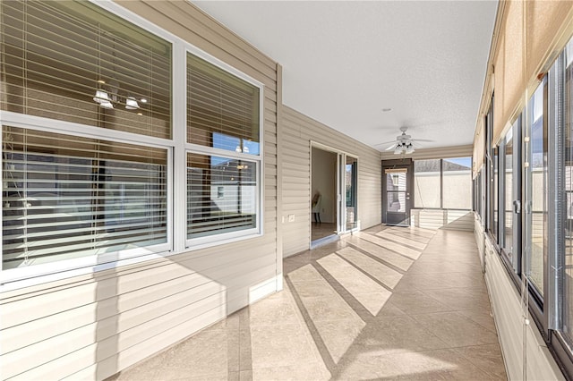 unfurnished sunroom featuring ceiling fan