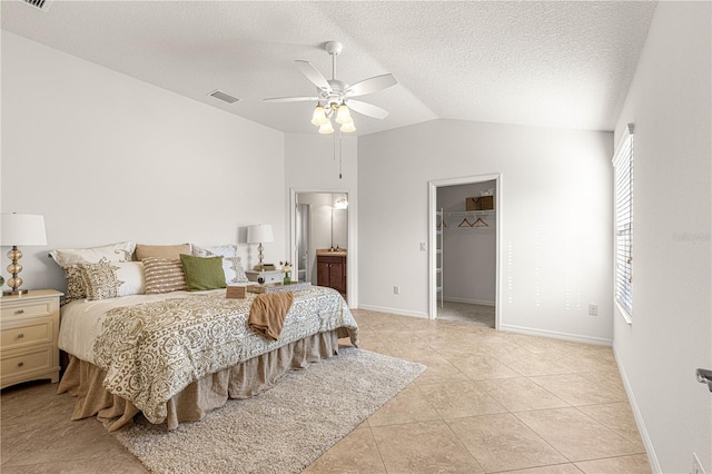 bedroom with ceiling fan, lofted ceiling, a textured ceiling, a walk in closet, and a closet