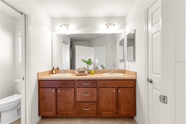 bathroom with a textured ceiling, vanity, and toilet