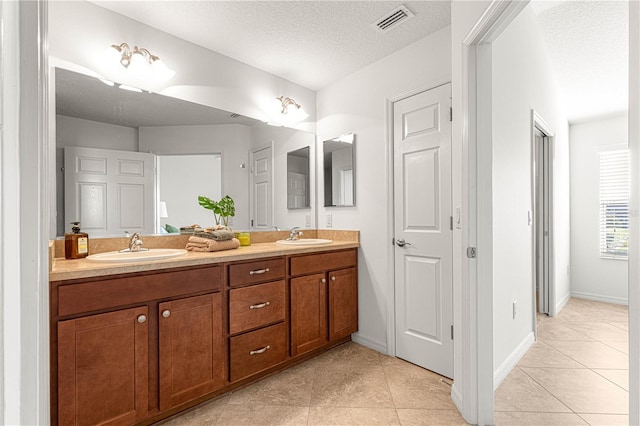 bathroom with tile patterned flooring, vanity, and a textured ceiling