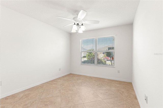 empty room with ceiling fan, light tile patterned floors, and a textured ceiling