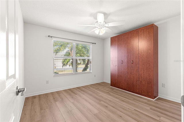 unfurnished bedroom with ceiling fan, light hardwood / wood-style floors, a textured ceiling, and a closet