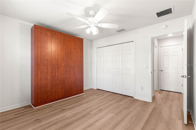 unfurnished bedroom with a textured ceiling, ceiling fan, light hardwood / wood-style flooring, and a closet