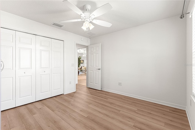 unfurnished bedroom featuring ceiling fan, light hardwood / wood-style floors, and a closet