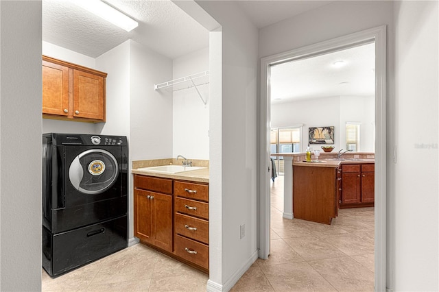 clothes washing area featuring sink, cabinets, a textured ceiling, washer / dryer, and light tile patterned flooring