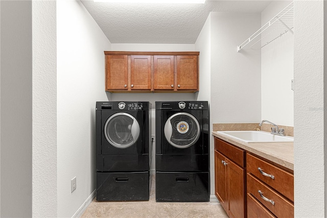 laundry area featuring cabinets, sink, independent washer and dryer, a textured ceiling, and light tile patterned floors