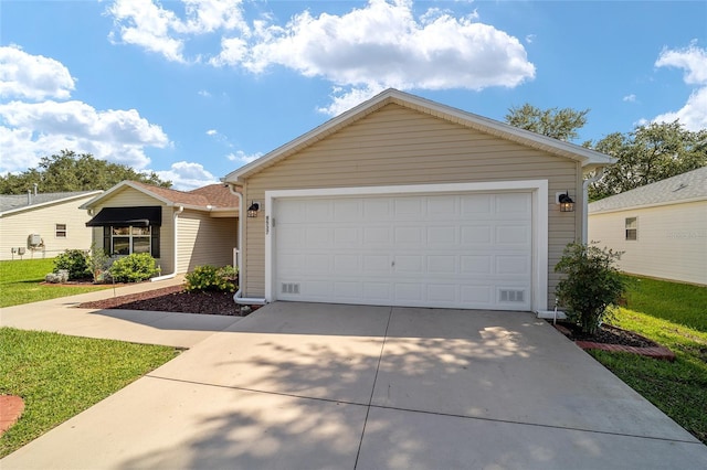 single story home featuring a garage, a front lawn, and concrete driveway