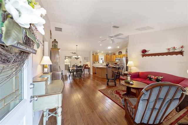 living room with vaulted ceiling, dark wood-type flooring, and visible vents