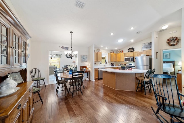 interior space featuring appliances with stainless steel finishes, a chandelier, a center island, vaulted ceiling, and hardwood / wood-style flooring