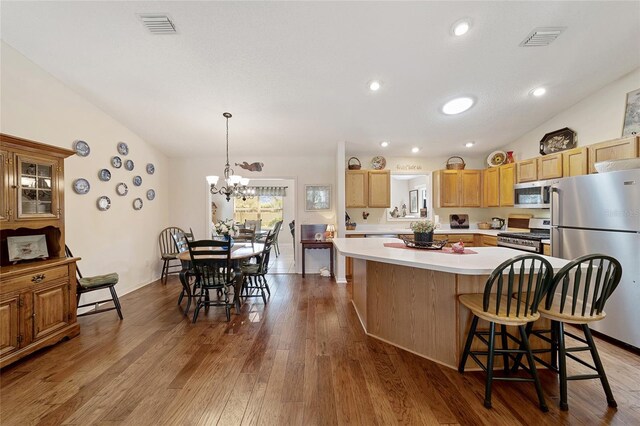 kitchen featuring stainless steel appliances, a chandelier, dark hardwood / wood-style flooring, a kitchen island, and vaulted ceiling