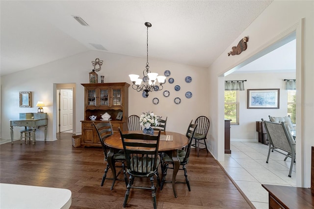 dining room with hardwood / wood-style flooring, an inviting chandelier, and lofted ceiling