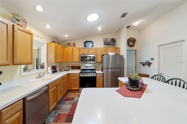 kitchen featuring lofted ceiling, light countertops, visible vents, appliances with stainless steel finishes, and a sink