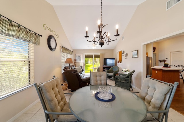 dining room featuring high vaulted ceiling, light tile patterned flooring, visible vents, and an inviting chandelier