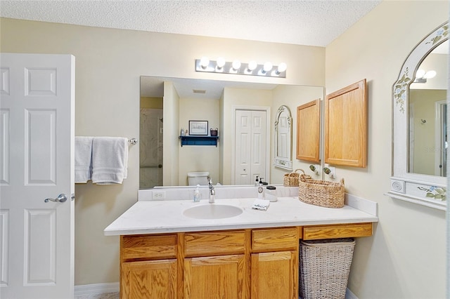 bathroom featuring a textured ceiling, toilet, and vanity