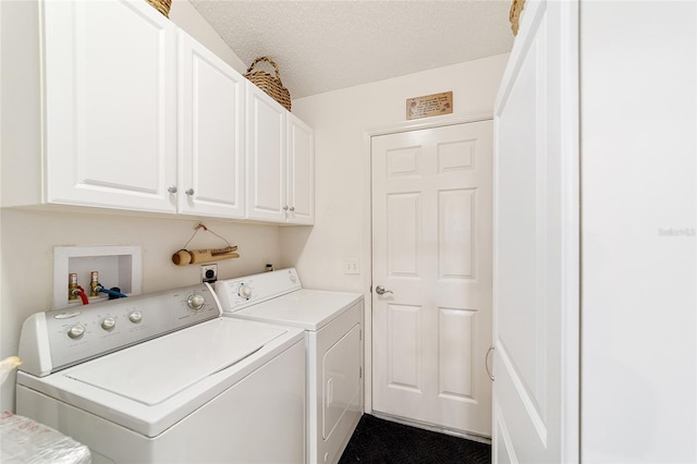 clothes washing area featuring a textured ceiling, washing machine and clothes dryer, and cabinets