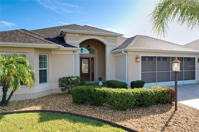 view of front facade featuring concrete driveway, roof with shingles, an attached garage, and stucco siding