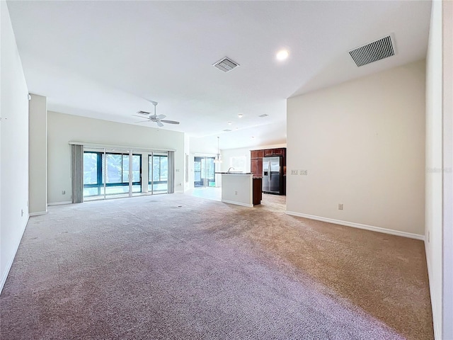 unfurnished living room with a ceiling fan, visible vents, light carpet, and baseboards