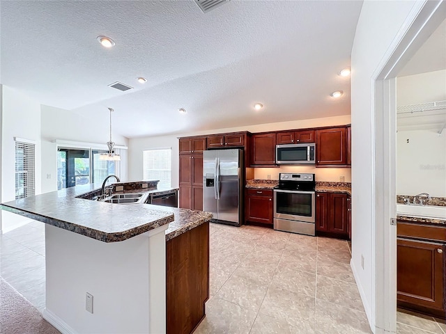 kitchen featuring visible vents, dark countertops, lofted ceiling, stainless steel appliances, and a sink