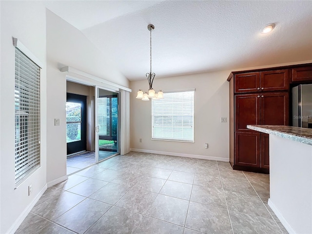 unfurnished dining area with vaulted ceiling, light tile patterned floors, baseboards, and an inviting chandelier