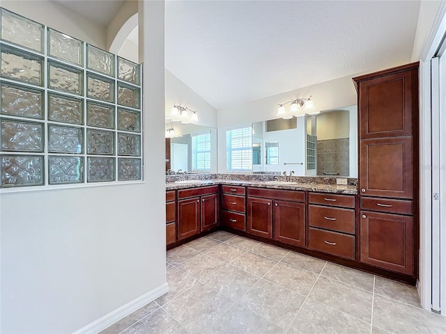 bathroom with tile patterned floors, vaulted ceiling, vanity, and a walk in shower