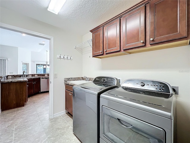 laundry room featuring a textured ceiling, a sink, visible vents, washer and dryer, and cabinet space